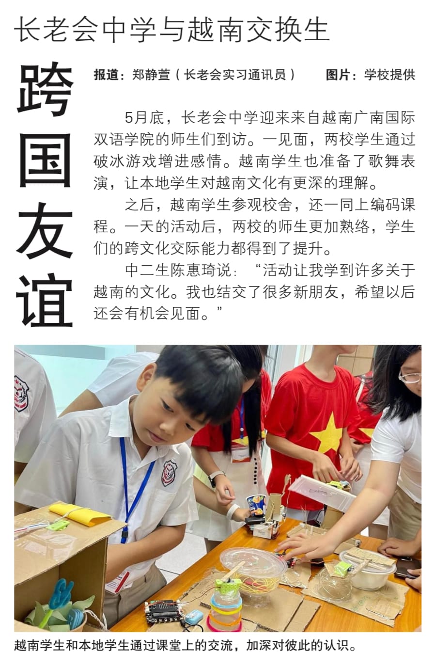 Students in school uniforms work together at a table covered with cardboard, electronics, and craft materials.